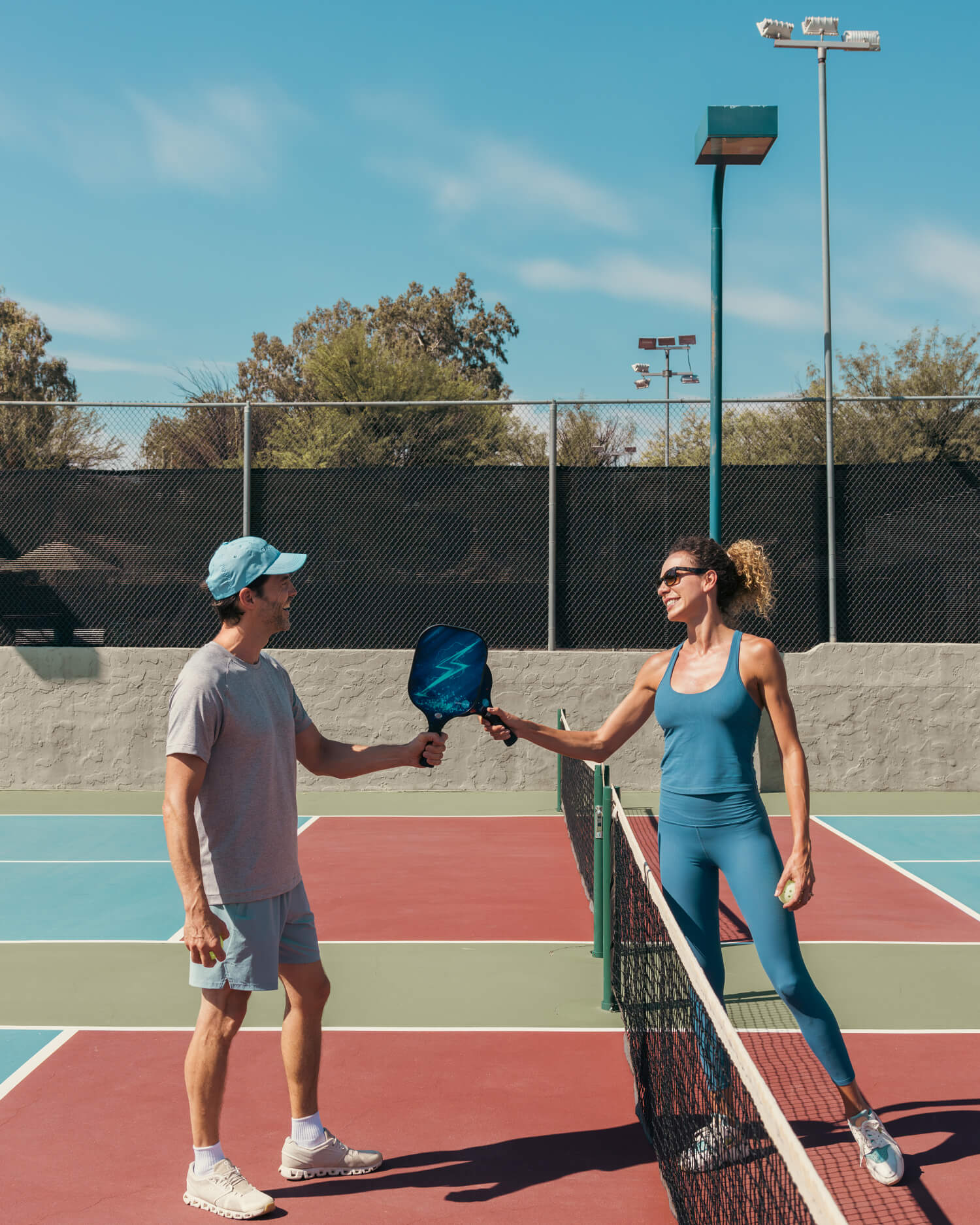 A man and a woman playing pickleball on an outdoor court.