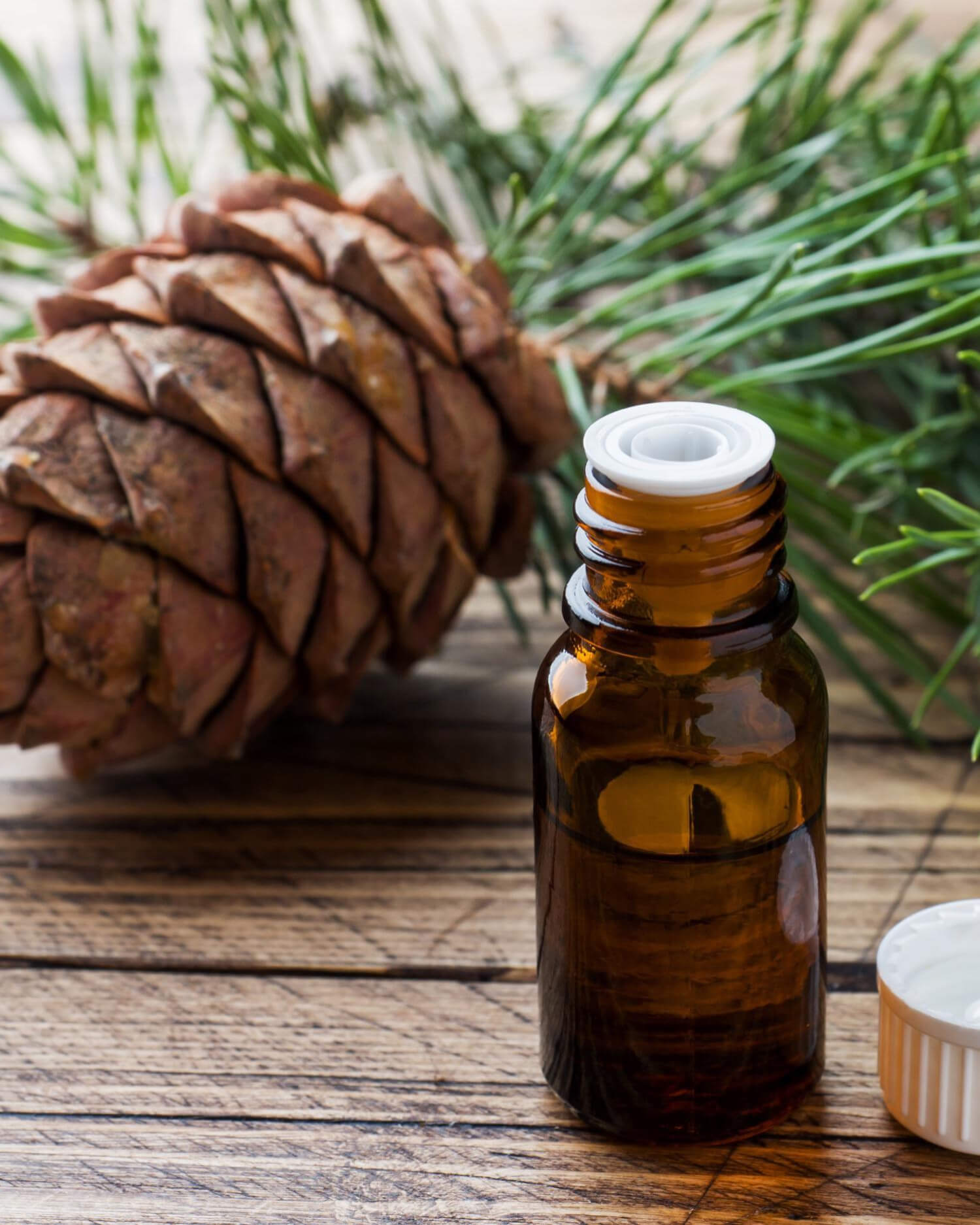 Bottle of essential oils on tabletop with Pine cone.