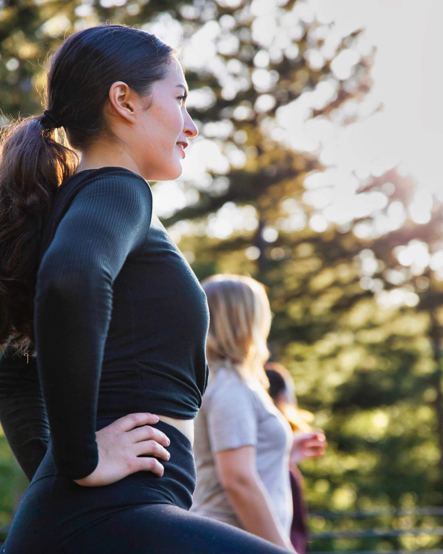 Women stretching outside with trees in the background