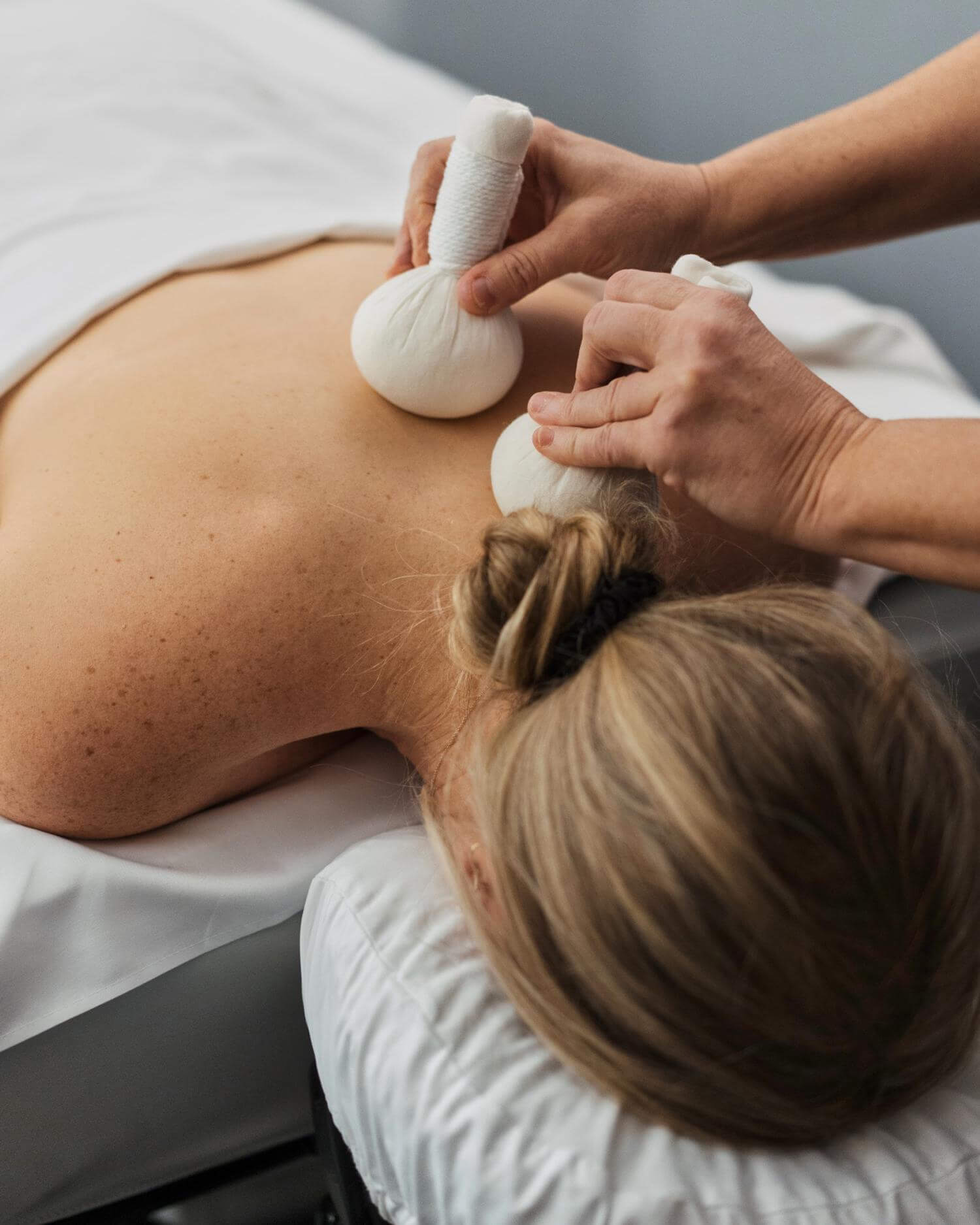 A woman receiving a Thai herbal poultice massage.