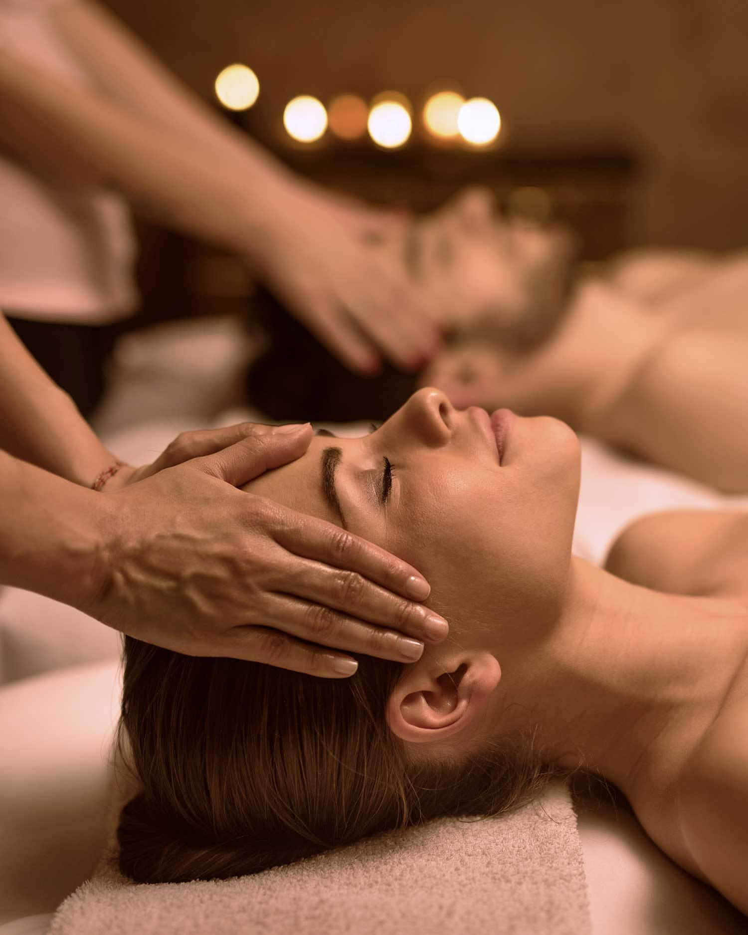 Couple receiving massages from massage therapists.